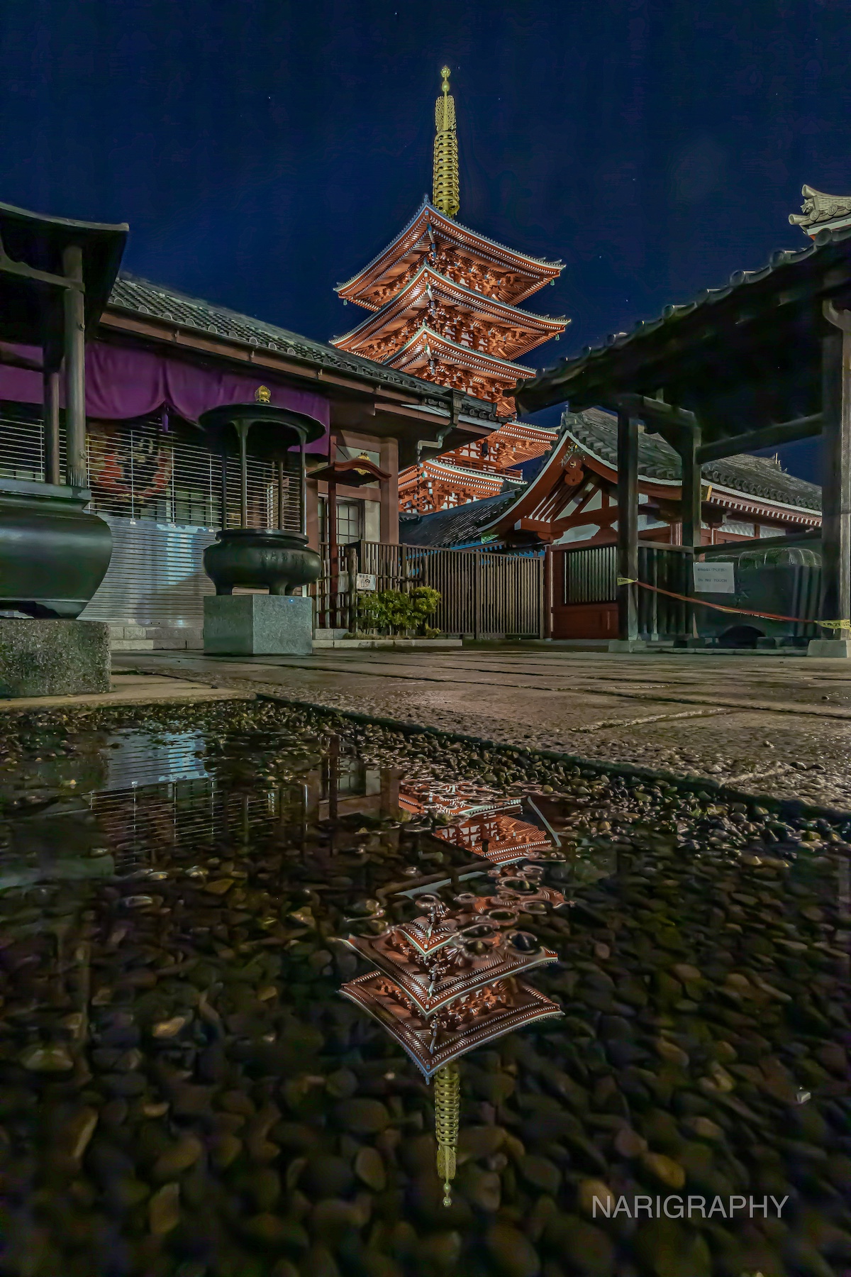 Reflection of Senso-ji Temple pagoda in a puddle at night, Tokyo Japan